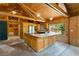 Cozy kitchen featuring wood-paneled ceiling and walls, island with cooktop, and natural light streaming in from a window at 6410 Amelia Ln, Dade City, FL 33523