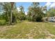 Expansive yard with lush greenery, mature trees, and a glimpse of nearby structures at 6410 Amelia Ln, Dade City, FL 33523