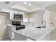 Modern kitchen with white cabinets, quartz counters, and stainless steel appliances with large breakfast bar at 6509 Pine Meadows Dr, Spring Hill, FL 34606