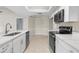 Modern kitchen featuring white cabinetry, stainless steel appliances, and a breakfast bar overlooking the dining area at 6509 Pine Meadows Dr, Spring Hill, FL 34606