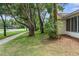 Exterior shot of the side yard with mature trees and a sidewalk at 6509 Pine Meadows Dr, Spring Hill, FL 34606