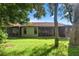 Exterior home view displaying a lush backyard and screened-in porch at 6590 Brambleleaf Dr, Spring Hill, FL 34606
