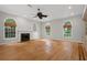 Bright living room featuring hardwood floors, a fireplace, arched windows, and built-in shelving at 7268 Crystal Spring Run, Weeki Wachee, FL 34607