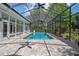 Indoor pool with screened ceiling, brick surround, and view of lush backyard at 7268 Crystal Spring Run, Weeki Wachee, FL 34607