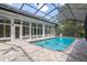 Indoor swimming pool enclosed with screened ceiling and white framed windows and doors at 7268 Crystal Spring Run, Weeki Wachee, FL 34607
