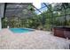 Enclosed swimming pool with screened ceiling, fan, hot tub, and brick patio at 7268 Crystal Spring Run, Weeki Wachee, FL 34607