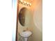 Cozy bathroom with pedestal sink, round mirror, and light fixture at 7650 Red Mill Cir, New Port Richey, FL 34653