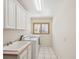 White laundry room features white appliances, tile floors, a sink and window at 8401 Pavilion Dr, Hudson, FL 34667