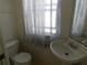 Compact bathroom featuring a pedestal sink, toilet, and a window with translucent curtains at 846 Burlwood St, Brandon, FL 33511