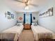 Bright bedroom with two twin beds, ceiling fan, carpeted floors, and beach themed decor at 8979 Hernando Way, Weeki Wachee, FL 34613