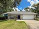 Inviting home featuring a two-car garage, manicured lawn, and a stone-accented facade at 8979 Hernando Way, Weeki Wachee, FL 34613
