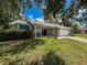 Single-story home with stone accents, manicured lawn, attached garage, and a cozy seating area on the porch at 8979 Hernando Way, Weeki Wachee, FL 34613