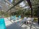 Sunlight filters through the screened pool enclosure illuminating lounge and dining areas at 8979 Hernando Way, Weeki Wachee, FL 34613