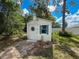 White storage shed with blue trim surrounded by landscaping and a stone path at 8979 Hernando Way, Weeki Wachee, FL 34613
