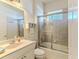 Bathroom featuring a tub with glass doors, a single sink, and neutral tiling at 9406 Burnam Dr, Weeki Wachee, FL 34613