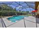 Enclosed pool with surrounding plants and landscaping and red umbrellas at 9406 Burnam Dr, Weeki Wachee, FL 34613