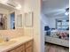 Bathroom with a wide mirror and sink leading to a bedroom with a floral bedspread at 9425 Sterling Ln, Port Richey, FL 34668