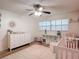 Bright Bedroom featuring a white crib, dresser, and soft pink accents, creating a calming space at 9425 Sterling Ln, Port Richey, FL 34668