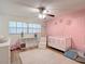 Cozy Bedroom with pink accent wall, white crib, and ceiling fan at 9425 Sterling Ln, Port Richey, FL 34668