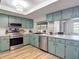 A bright, fully equipped kitchen with stainless steel appliances, wood floors, and light green cabinets at 9425 Sterling Ln, Port Richey, FL 34668