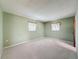 Empty bedroom showcases light green walls, plush carpet flooring, and two windows with curtains at 11094 Auburndale St, Spring Hill, FL 34609