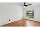 Cozy bedroom showcasing wood floors, a ceiling fan, and a bright window overlooking the front yard at 11725 Spring Tree Ln, Port Richey, FL 34668