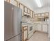 Functional kitchen featuring white cabinetry, stainless refrigerator, and tile floor at 11725 Spring Tree Ln, Port Richey, FL 34668