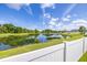 Scenic view of a tranquil pond surrounded by lush greenery and a white fence at 12119 Barnsley Reserve Pl, Gibsonton, FL 33534