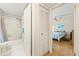 Bathroom leading to a bedroom with wood floors, a ceiling fan, and blue bedding at 12141 Spartan Way # 102, Hudson, FL 34667
