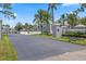 Community entrance with gray walls, lush green lawns, and mature palm trees at 12141 Spartan Way # 102, Hudson, FL 34667