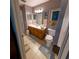 Well-lit bathroom features a vanity with a wooden cabinet, a mirror, and neutral-colored tiles at 13651 Forest Lake Dr, Largo, FL 33771