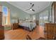 This bedroom features light green walls, wood floors, ceiling fan and sliding glass doors to the backyard at 14178 Pullman Dr, Spring Hill, FL 34609