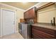 Laundry room boasts wooden cabinets, granite countertop, and newer model washer and dryer at 1478 Brigadier Dr, Spring Hill, FL 34608