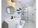 Bathroom with black fixtures, shower, white vanity and stylish round mirror at 1652 Larkin Rd, Spring Hill, FL 34608