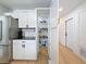 Pantry and hallway with white cabinets, stainless steel fridge, and laminate floors at 1652 Larkin Rd, Spring Hill, FL 34608