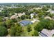 An aerial view captures a residence with a pool, nestled among mature trees in a residential neighborhood at 2111 Maximilian Ave, Spring Hill, FL 34609
