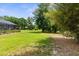 Large backyard with lawn, mature trees, landscaping, and screened pool at 2111 Maximilian Ave, Spring Hill, FL 34609