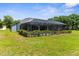 Backyard view of screened pool and landscaped lawn at 2111 Maximilian Ave, Spring Hill, FL 34609