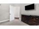 Carpeted bedroom with a dresser, open doorway and a mounted television at 2111 Maximilian Ave, Spring Hill, FL 34609