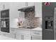 Close-up of a modern kitchen with stainless steel appliances, a gray refrigerator, and tiled backsplash at 2111 Maximilian Ave, Spring Hill, FL 34609