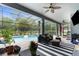 Covered patio with seating, grill, TV, and view of the screened pool area at 2111 Maximilian Ave, Spring Hill, FL 34609