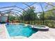 Screened pool and hot tub with sun loungers and wooded view at 2111 Maximilian Ave, Spring Hill, FL 34609