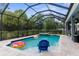 Screened pool with hot tub, blue lounge chair, and inflatable donuts at 2111 Maximilian Ave, Spring Hill, FL 34609