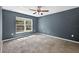 Bedroom with a ceiling fan, neutral carpet, and a window allowing plenty of natural light at 2476 Magellan Ave, Spring Hill, FL 34608