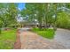 Brick driveway leads to a luxury home with lush landscaping, mature trees, and a gravel parking area at 26221 Pheasant Run, Wesley Chapel, FL 33544