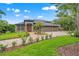 Elegant home featuring stone accents, three car garage, mature landscaping, and a beautiful brick driveway at 26221 Pheasant Run, Wesley Chapel, FL 33544