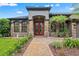 Elegant front entrance with a brick walkway, stone accents, and red double doors at 26221 Pheasant Run, Wesley Chapel, FL 33544