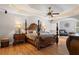 Elegant main bedroom featuring hardwood floors, a four-poster bed, tray ceilings, and accent lighting at 26221 Pheasant Run, Wesley Chapel, FL 33544