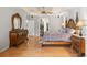 Spacious main bedroom showcasing hardwood floors, a king-size bed, and a beautiful dresser with large mirror at 26221 Pheasant Run, Wesley Chapel, FL 33544