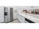 Well-appointed kitchen with white cabinets, stainless steel refrigerator, and a pass-through to the dining area at 3204 Payne St, New Port Richey, FL 34655
